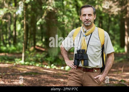 Portrait de l'homme adulte à la taille en tant que chef de scout regardant la caméra à l'extérieur dans la forêt et souriant, copier l'espace Banque D'Images