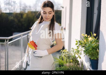 Jeune femme attrayante dans l'ensemble avec les outils de jardin se tiennent sur le balcon et se préparant à l'atterrissage Banque D'Images