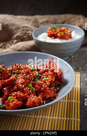 Yangnyeom Tongdak (poulet frit épicé coréen) ailes de poulet épicées en sauce aigre-douce sur fond rustique Banque D'Images