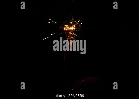 Lumière et étincelles provenant d'une lampe à incandescence qui brûle. Court-circuit Banque D'Images