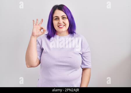 Plus taille femme avec cheveux violets debout sur fond isolé sourire positif faisant ok signe avec la main et les doigts. expression réussie. Banque D'Images