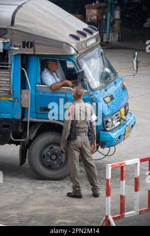 SAMUT PRAKAN, THAÏLANDE, OCT 07 2022, Un policier parle au conducteur d'un vieux camion transportant des personnes Banque D'Images