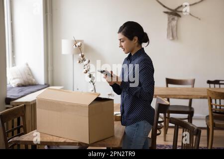 Femme prépare la boîte en carton pour l'expédition en utilisant les services de messagerie en ligne Banque D'Images