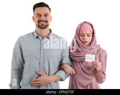 Une femme musulmane meurtrisée tenant du papier avec du texte, je Vais BIEN et son mari sur fond blanc. Concept de violence domestique Banque D'Images