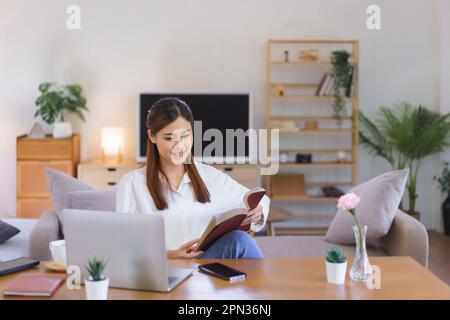 Concept de temps de détente, les femmes lisant la sainte bible après avoir travaillé avec un ordinateur portable dans un bureau à domicile moderne. Banque D'Images