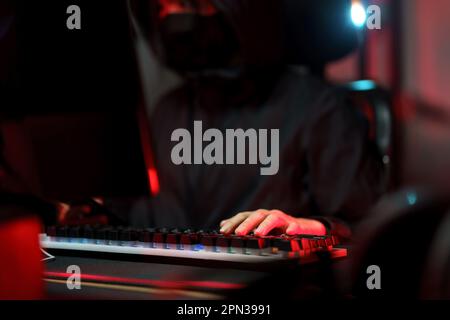 Hacker en hoodie travaillant sur l'ordinateur et en tapant sur le clavier pour le piratage du système de programmation ou du serveur. Banque D'Images