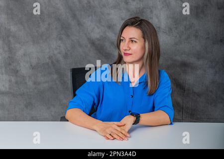 une femme pensive dans une chemise bleue est assis Banque D'Images