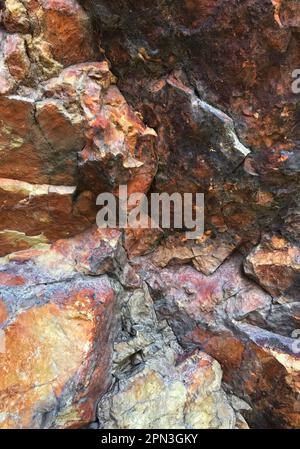 Formation de roche ignée extrusive à la rhyolite. Les couleurs proviennent des minéraux : fer oxydé (orange/rouge/jaune), magnésium (noir) et silice (blanc) Banque D'Images