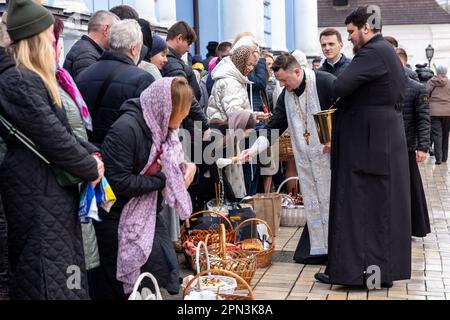 Un prêtre bénit la nourriture de Pâques avec l'eau sainte comme les croyants ukrainiens participent à la célébration traditionnelle du dimanche de Pâques à Saint Monastère à la Domée d'or de Michael, dans le centre de Kiev, la capitale de l'Ukraine sur 16 avril 2023. Selon la tradition, les fidèles apportent leur nourriture de Pâques dans un panier à purifier, il est toujours Pasha (pain de Pâques), oeuf peint (pysanka) entre autres. La plupart des Ukrainiens sont des chrétiens orthodoxes ou des chrétiens catholiques grecs, tous deux observent le rite oriental de Pâques. Kiev reste relativement pacifique alors que l'invasion russe se poursuit et que l'Ukraine se prépare pour un pays de printemps Banque D'Images