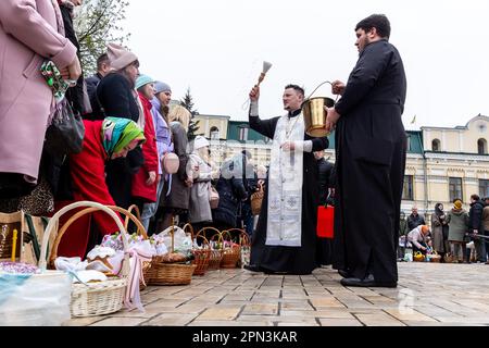 Un prêtre bénit la nourriture de Pâques avec l'eau sainte comme les croyants ukrainiens participent à la célébration traditionnelle du dimanche de Pâques à Saint Monastère à la Domée d'or de Michael, dans le centre de Kiev, la capitale de l'Ukraine sur 16 avril 2023. Selon la tradition, les fidèles apportent leur nourriture de Pâques dans un panier à purifier, il est toujours Pasha (pain de Pâques), oeuf peint (pysanka) entre autres. La plupart des Ukrainiens sont des chrétiens orthodoxes ou des chrétiens catholiques grecs, tous deux observent le rite oriental de Pâques. Kiev reste relativement pacifique alors que l'invasion russe se poursuit et que l'Ukraine se prépare pour un pays de printemps Banque D'Images