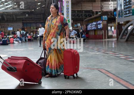 Une femme indienne voyageur, vêtue d'un sari coloré, tirant ses bagages à travers (gare) Chhatrapati Shivaji Maharaj Terminus; Mumbai, Inde Banque D'Images