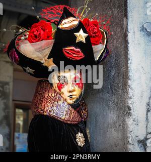 Participant au carnaval de Venise en costume coloré, gros plan de la tête de femme en masque, chapeau et robe de fantaisie, Venezia, Italie Banque D'Images