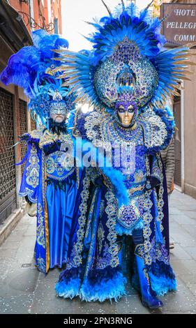 Venice Carnivale, deux participants en bleu turquoise vénitien baroque paon costume inspiré avec plumes, masque et chapeau, Venezia, Italie Banque D'Images