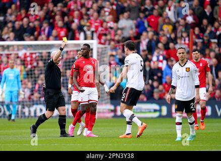 L'arbitre Simon Hooper (à gauche) présente une carte jaune au Harry Maguire de Manchester United après une faute sur Taiwo Awoniyi de la forêt de Nottingham lors du match de la Premier League au City Ground, à Nottingham. Date de la photo: Dimanche 16 avril 2023. Banque D'Images