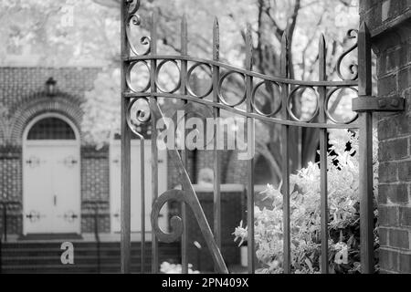 Porte en fer forgé ouverte et accueillante dans le jardin de l'église. Banque D'Images