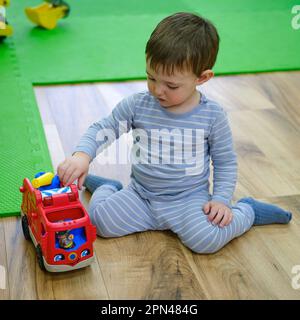 Bébé joue avec des jouets dans la maternelle. Un petit garçon heureux dans la salle de jeux. Enfant âgé d'un an neuf mois Banque D'Images