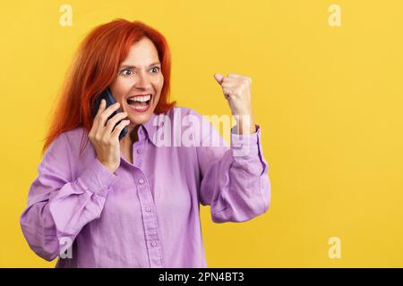 Bonne femme mûre à la tête en train de célébrer tout en emportant sur le mobile Banque D'Images