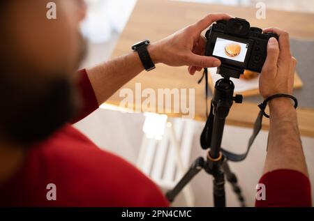 Rogné d'un photographe masculin tenant un appareil photo, prenant une photo de hamburger Banque D'Images