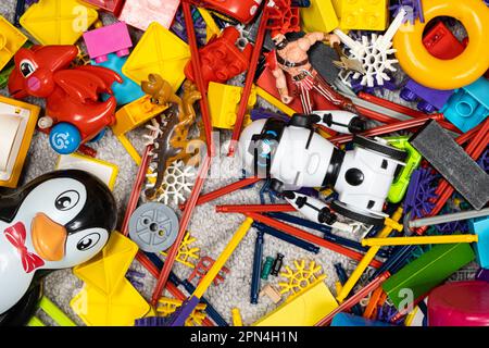 Une abondance de jouets dans la chambre des enfants, beaucoup de pièces en plastique multicolores de designers, pièces de rechange pour jouets, figurines et cubes. Banque D'Images