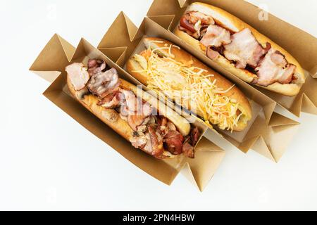 Délicieux hot dog grillé dans un restaurant, hot dogs faits maison enveloppés de bacon, avec oignons et champignons, salade. Nourriture de rue, livraison, plats à emporter, nourriture Banque D'Images