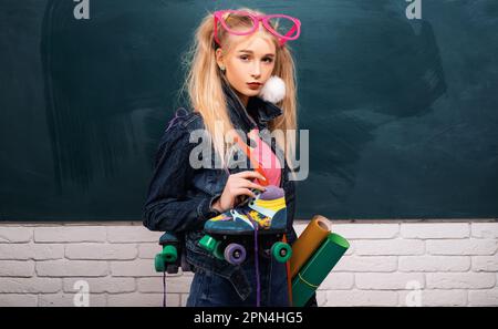 École adolescent. Vêtements taille basse fille avec fille dans accessoires de mode. Un design minimaliste aux couleurs douces. Adorable adolescent devant le tableau noir Banque D'Images