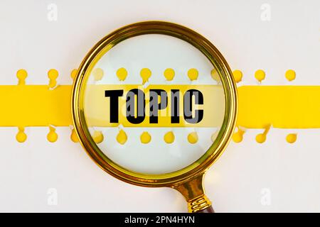 Entre deux feuilles d'un bloc-notes sur une bande jaune avec l'inscription - sujet, il y a une loupe. Concept d'entreprise. Banque D'Images