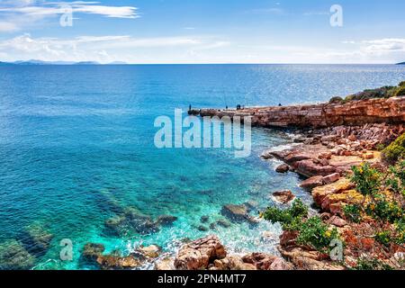 Personnes pêchant sur une plage rocheuse de l'est d'Attica, Grèce un jour ensoleillé. Banque D'Images