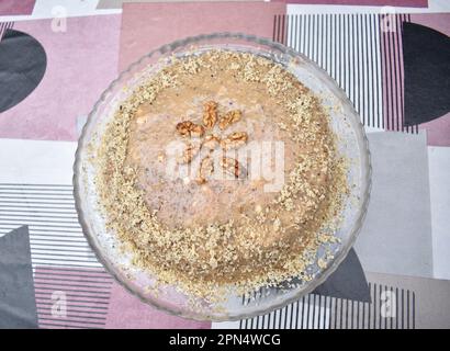 Vue de dessus d'un gâteau au caramel maison décorant avec des chapelure de noix et de noix sur une assiette transparente et une table colorée. Banque D'Images