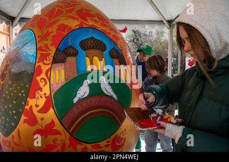 Moscou, Russie. 16th avril 2023. Un artiste peint des maquettes de deux mètres d'oeufs de Pâques pendant la saison d'art dans le cadre du Festival de cadeau de Pâques, le jour de Pâques orthodoxe dans la rue Petrovka près du monastère de Vysokopetrovsky à Moscou, en Russie. Le thème de la peinture est l'héroïsme au sens large : à commencer par les images des héros russes, des épopées et des contes de fées aux héros modernes. Banque D'Images