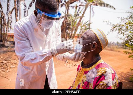 Un médecin africain effectue un test nasal par écouvillonnage sur un patient âgé. Banque D'Images