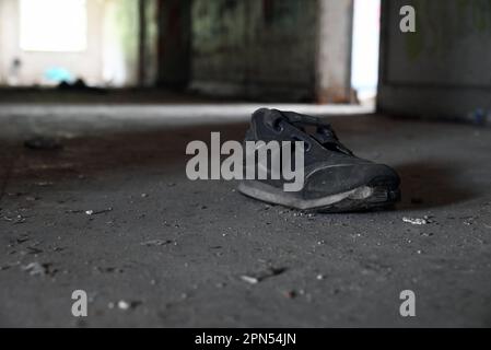 La chaussure abandonnée d'un enfant repose dans un couloir d'une école qui a été abandonnée et vandalisée depuis 2001. Banque D'Images