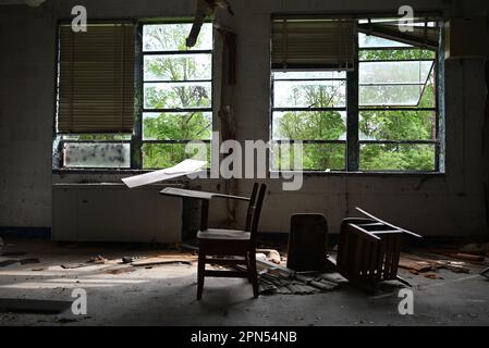 Une paire de bureaux d'étudiants jetés dans une salle de classe remplie de débris dans une école abandonnée depuis 2001. Banque D'Images