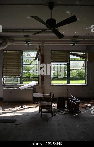 Une paire de bureaux d'étudiants jetés dans une salle de classe remplie de débris dans une école abandonnée depuis 2001. Banque D'Images