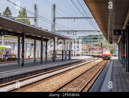 Un train suisse rouge s'approche de la gare de Spiez, sur le lac Thun, dans l'Oberland bernois, en Suisse Banque D'Images