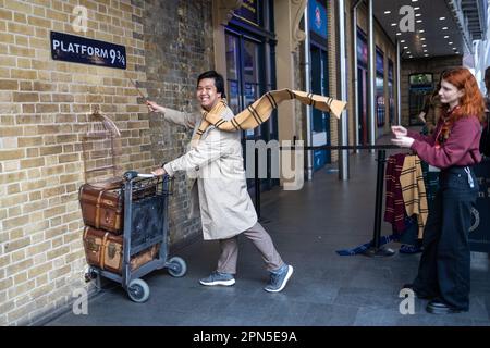 LONDRES, ANGLETERRE - 15 avril 2023 fan de Harry Potter recrée pousser un chariot vers la plate-forme neuf et trois quarts du film Banque D'Images
