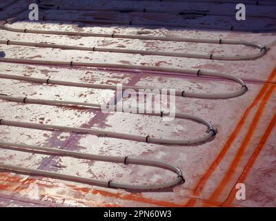 Les boucles des serpentins thermiques dans le plancher sont lues pour l'installation sur une isolation en mousse de polystyrène. Banque D'Images