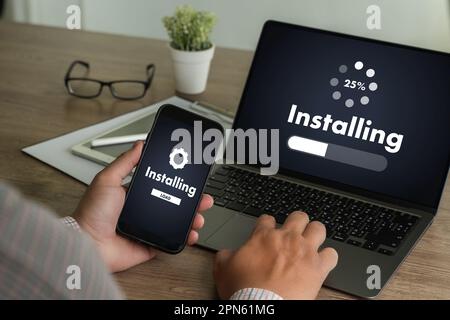 Homme installant la mise à jour de logiciel sur les communications de technologie numérique de téléphone mobile et d'ordinateur portable Banque D'Images