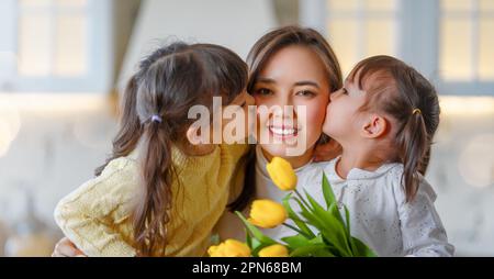 Bonne journée mère. Enfants filles félicitant la mère et donnant son bouquet de fleurs. Banque D'Images