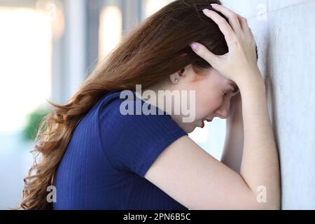 Vue latérale d'une femme triste se plaignant penchée dans un mur Banque D'Images