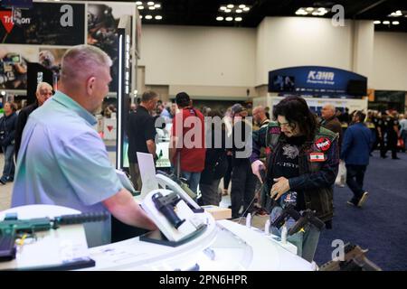 Indianapolis, États-Unis. 16th avril 2023. Un client essaie une arme de poing et un étui lors des réunions et expositions annuelles de la National Rifle Association au centre de congrès de l'Indiana à Indianapolis. La convention, qui devrait attirer environ 70 000 invités a ouvert vendredi. Crédit : SOPA Images Limited/Alamy Live News Banque D'Images