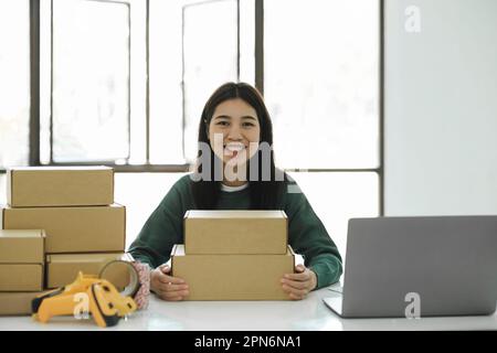 Femme en ligne propriétaire d'affaires tenant le colis et regardant le chamer Banque D'Images