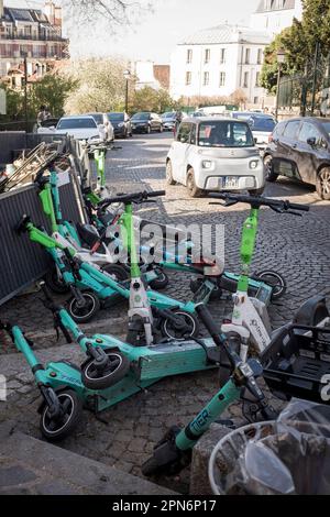 Location de trottinettes de différentes sociétés garées et tombées dans une rue de Montmartre, Paris, France. Banque D'Images