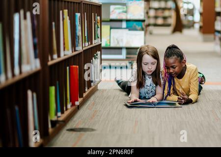 Deux jeunes filles lisant un livre à l'étage de la bibliothèque Banque D'Images