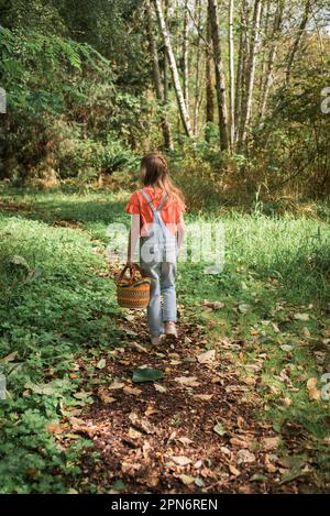 Fille marchant dans les bois avec le panier Banque D'Images