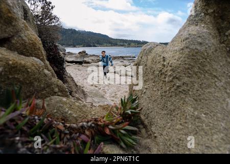 Un garçon encadré par Rocks à la plage part de Camera Banque D'Images