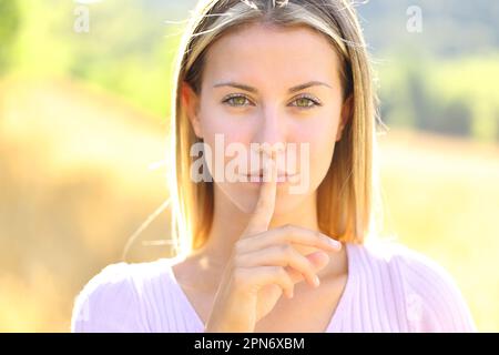 Vue de face portrait d'une belle femme demandant le silence dans la nature Banque D'Images