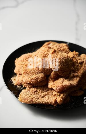 Poulet cru schnitzel billet es calliope dans la chapelure. Sur fond de marbre blanc. Banque D'Images