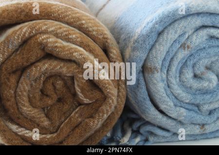 Couverture en tissu écossais à carreaux en laine isolée sur un fond blanc. Couverture roulée beige-brun et blanc-bleu. Gros plan. Banque D'Images