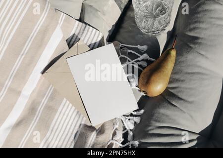Vacances d'été encore la vie. Gros plan sur une carte de vœux vierge, maquette d'invitation. Serviette de plage à rayures beiges. Composition de lit de soleil avec fruits de poire frais Banque D'Images