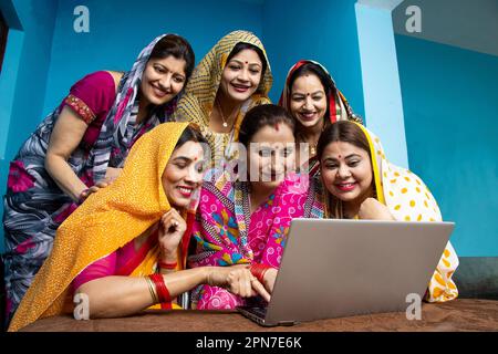 Groupe de jeunes femmes indiennes traditionnelles portant sari apprennent à utiliser un ordinateur portable ou un ordinateur. La technologie dans les ménages ruraux. compétence inde. Banque D'Images